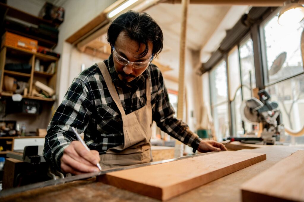 Mature carpenter measuring wood in a workshop